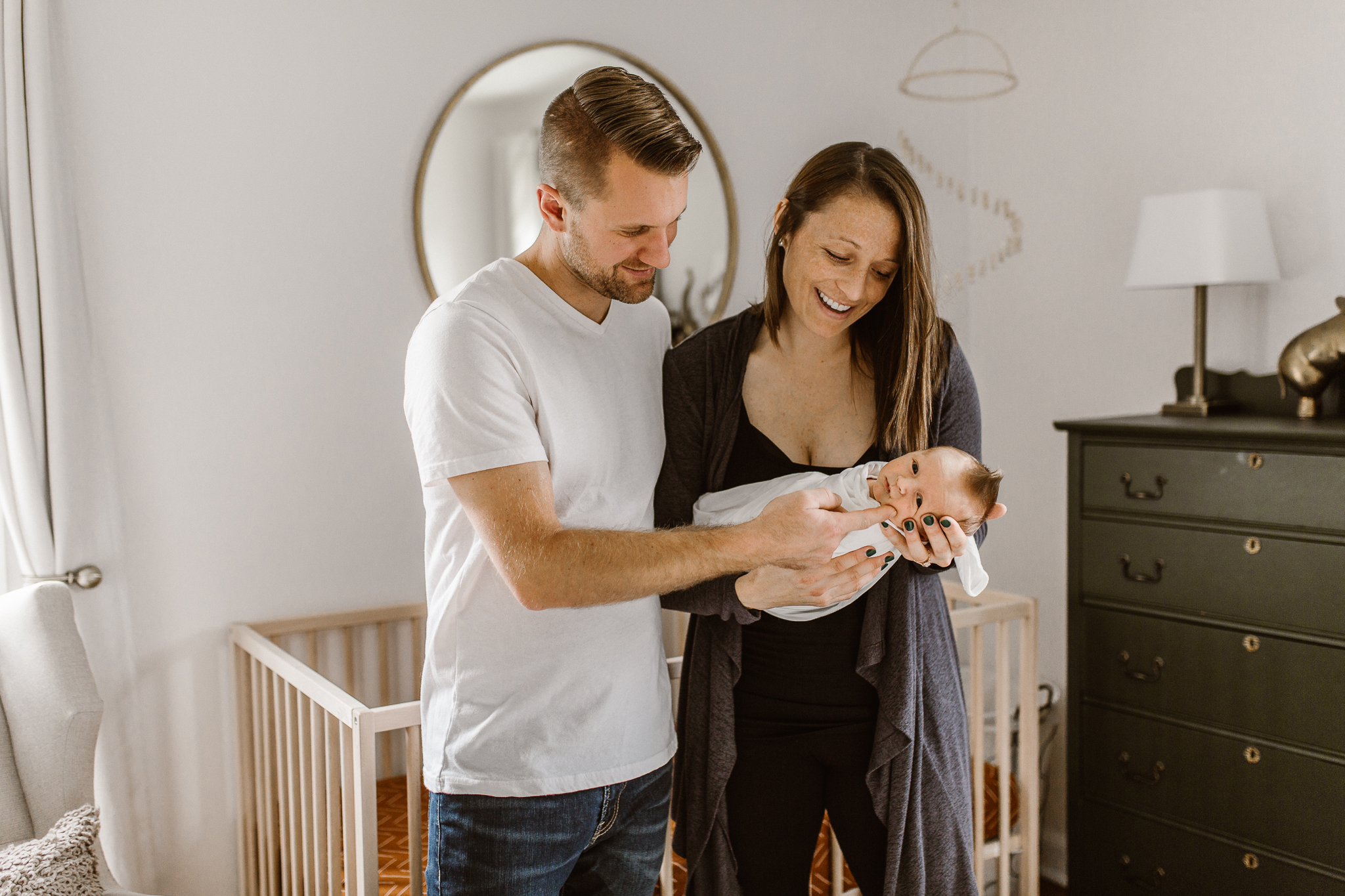 New parents in the nursery smiling down at their son.